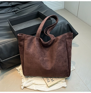 Close-up of deep brown suede tote bag featuring a wide shoulder strap and premium matte texture