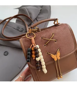 Close-up of brown vintage bag featuring beaded tassels and golden butterfly pendant detail