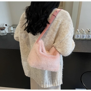 Dettaglio della borsa a spalla in ecopelliccia rosa indossata su un maglione chiaro