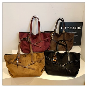 Detail of suede tote bags in burgundy, brown, and black with ethnic beaded tassels