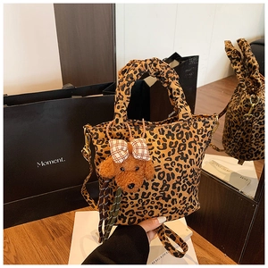 Detail of leopard print tote bag with ruched handles and a cute puppy plush charm