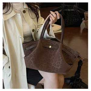 Détail du sac cabas vintage imprimé léopard avec boucle dorée sur un trench-coat beige