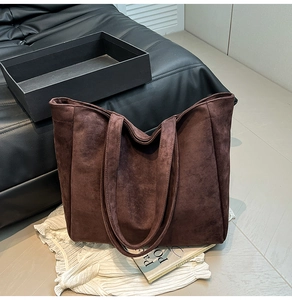Detail of minimalist coffee brown matte suede tote bag on leather sofa for autumn