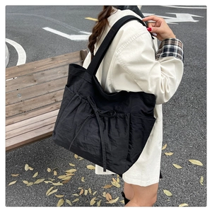 Detail of black large capacity canvas tote bag with side pockets and bow tie decoration