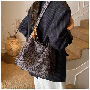 Detail of leopard print hobo bag with wide shoulder strap and wooden bead tassel decor