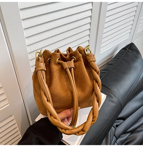Détail d'un sac seau en daim marron avec poignée tressée et fermeture à cordon