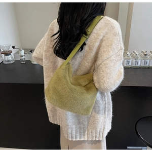 Borsa a secchiello in peluche verde erba indossata da modella su maglione lavorato