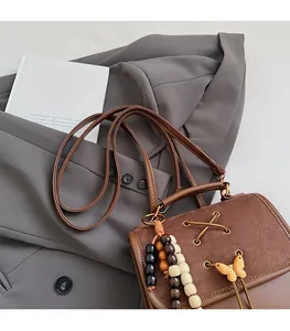 Detail of vintage brown backpack featuring decorative wood beads and a stylish bow charm