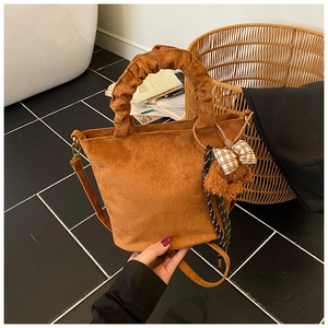 Detail of vintage brown suede bucket bag with a plush bear charm and pleated handle
