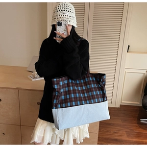 Détail du grand sac cabas en toile à carreaux bleus et marron dans un cadre chaleureux