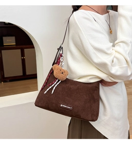 Détail du sac cabas en daim marron foncé avec breloque ours en peluche et étiquette