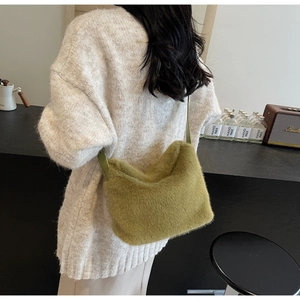 Dettaglio di una borsa a tracolla in ecopelliccia verde indossata su un maglione beige