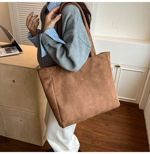 Detail of a large brown suede tote bag styled with a minimalist outfit for a commute look