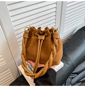 Détail du sac seau en daim marron avec poignée torsadée et ferrures en métal doré