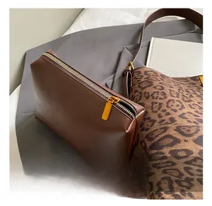 Close-up of golden metal zipper on brown leather pouch and leopard print tote bag texture