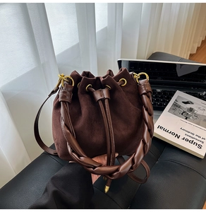 Détail du sac seau en daim marron foncé avec poignée tressée et boucles dorées