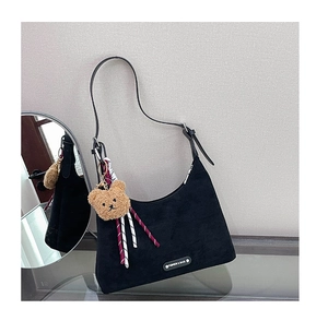 Détail du sac hobo en daim noir avec bandoulière en cuir et breloque ours marron