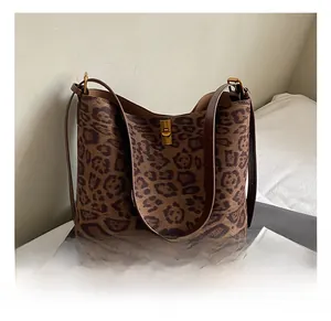 Close-up detail of leopard print tote bag with brown leather straps and gold metal twist lock