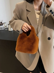 Brown faux fur bucket bag with silver chain strap shown on a model in a casual city setting