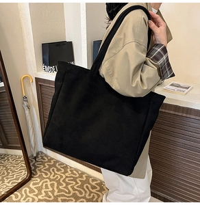 Side view of large black faux suede tote bag worn by a model for daily use