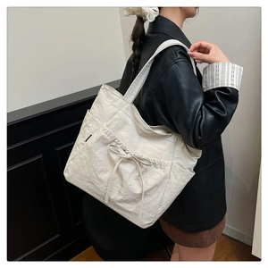 Detail of off-white nylon tote bag with drawstring bow and convenient side pocket
