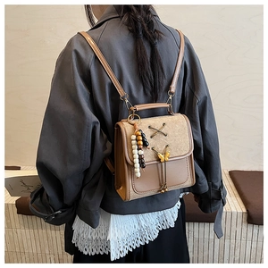 Detail of vintage brown backpack with ribbon ties, metal butterfly and wooden beads