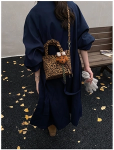 Detailed leopard print tote bag with bear charm and bow decoration on a shoulder strap