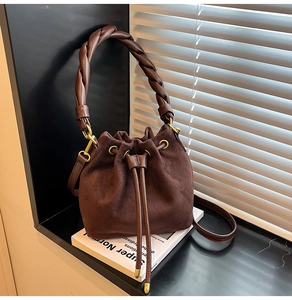 Détail du sac seau en daim marron foncé avec poignée tressée épaisse et fermeture à cordon