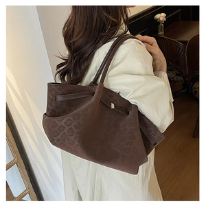 Sac fourre-tout marron à motif léopard porté par un mannequin dans un café chic