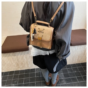 Close-up of brown vintage backpack with bow detail and wood beads on a person