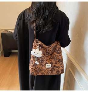 Detail of paisley pattern shoulder bag with a cute white cloud plush charm and label