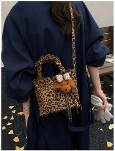 Detail of leopard print canvas tote bag with ruffles handle and brown puppy plush pendant