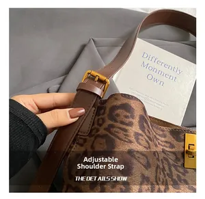 Detail of adjustable leather shoulder strap with gold metal buckle on leopard print bucket bag