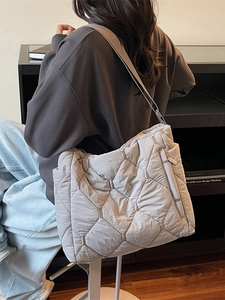 Quilted light gray tote bag with diamond stitching shown in a minimalist lifestyle setting