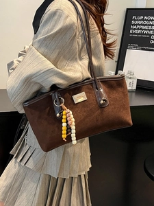 Brown suede tote bag with stylish wooden bead charm and sleek shoulder strap