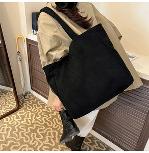 Macro detail of spacious black faux suede tote bag with wide strap for daily commute
