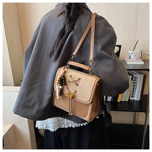 Close-up of retro brown PU leather backpack with bow-knot clasp and bead tassel detail
