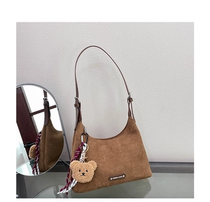 Détail du sac hobo en daim marron avec bandoulière réglable et breloque petit ours