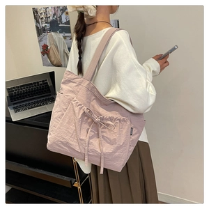 Detail of light pink pleated canvas tote bag with drawstring bow and side fashion label
