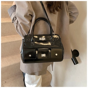 Détail du sac en cuir verni noir avec des fermoirs argentés et plusieurs poches chic
