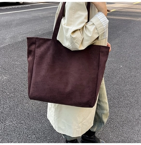 Detail of burgundy oversized suede tote bag with long straps worn on shoulder