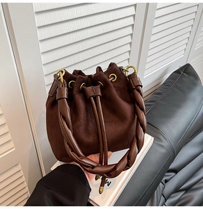 Vue détaillée du sac seau en daim marron avec poignée tressée et fermeture à cordon