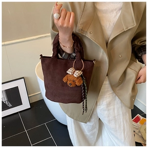 Detail of coffee suede tote bag featuring a cute teddy bear charm and soft handle