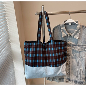 Détail d'un grand sac cabas à carreaux avec larges anses dans un cadre minimaliste