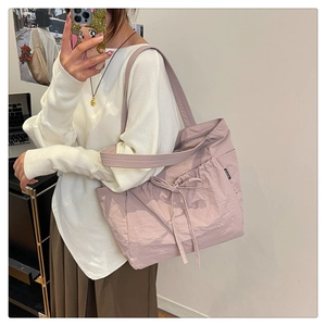 Detail of pink nylon tote bag featuring side drawstring pleats and a FASHION woven label