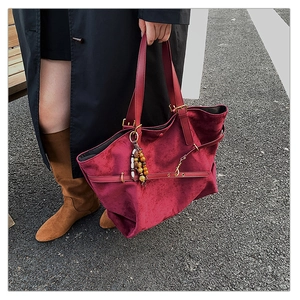 Macro shot of burgundy velvet tote bag detailing beaded charm and premium suede texture