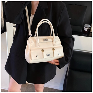 Détail d'un sac à main blanc crème brillant avec deux poches frontales et fermoirs rotatifs
