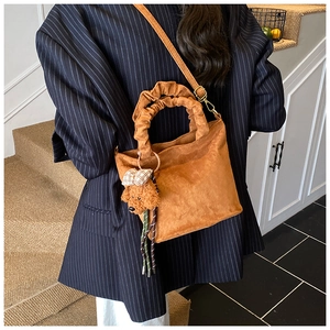 Brown faux suede bucket bag with pleated handle and cute poodle charm accessory