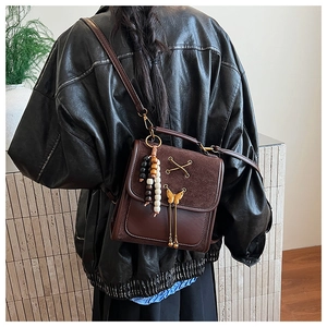 Detail of vintage brown leather crossbody bag with metal bow buckle and wooden bead charm