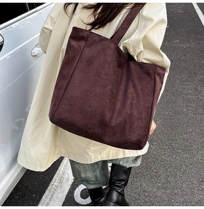 Detail of a large dark brown suede tote bag with a wide shoulder strap for autumn